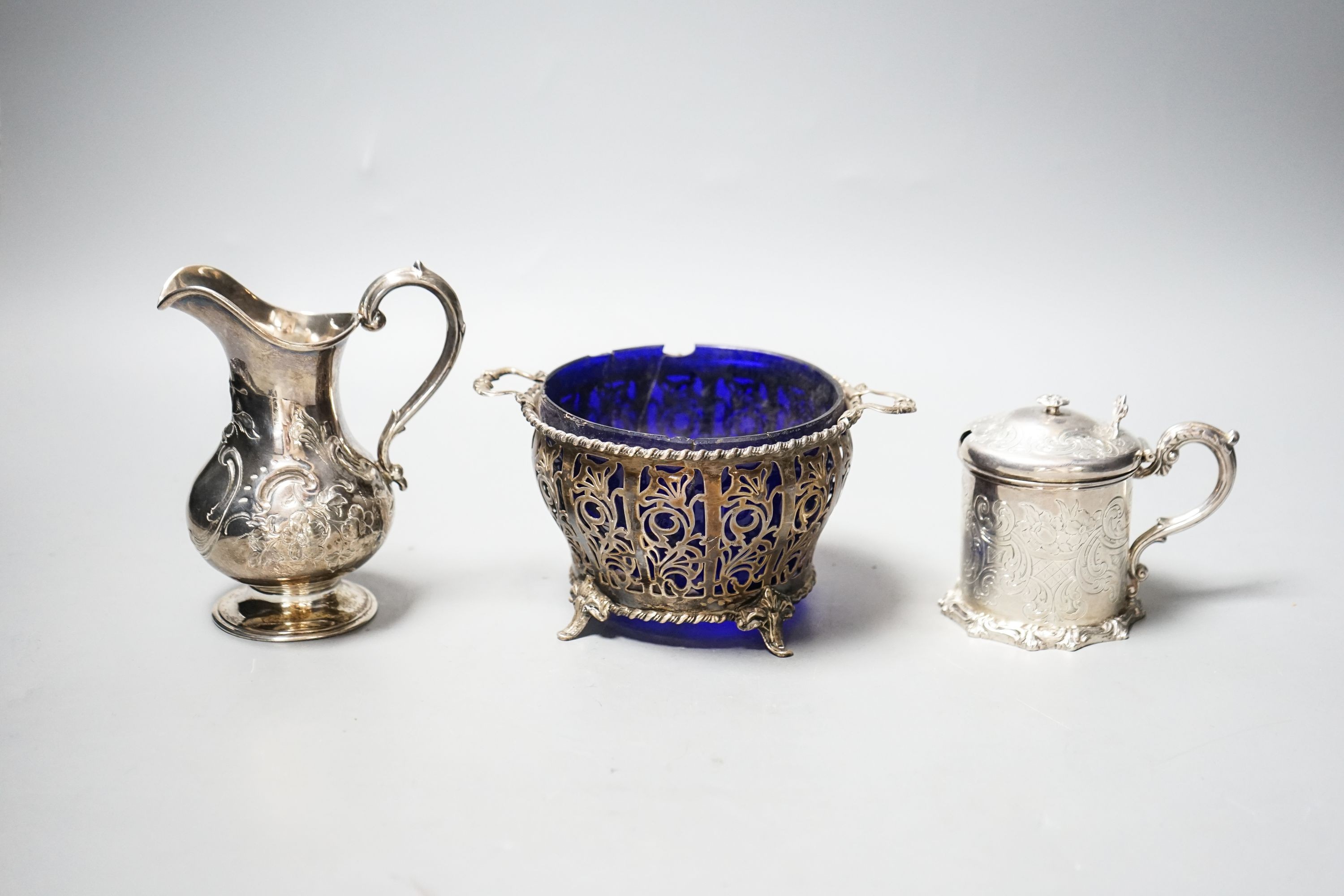 A Victorian silver cream jug, London, 1851, a Victorian silver mustard and a 1930's pierced silver two handled bowl, with blue glass liner.
